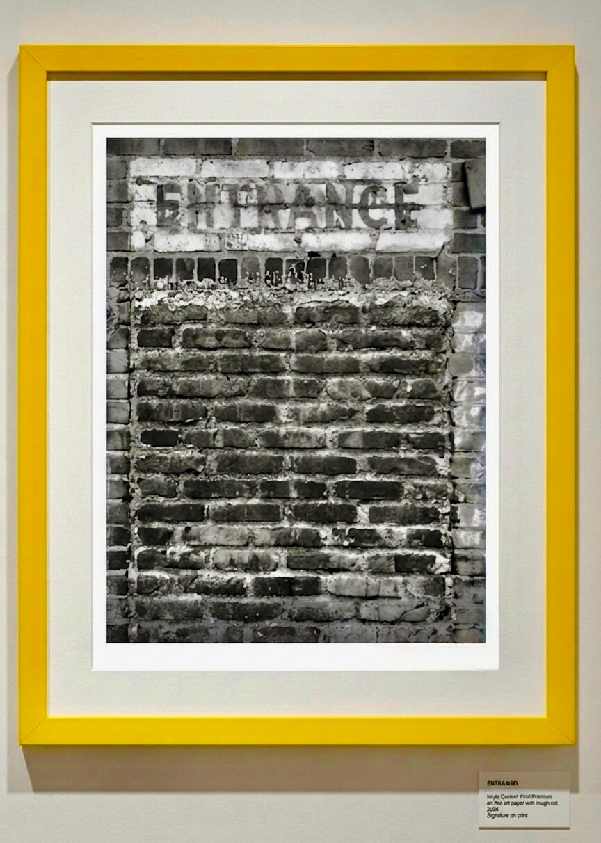 tractor & entrance at TAG Gallery The photograph shows a weathered brick wall with a rectangular sign above.